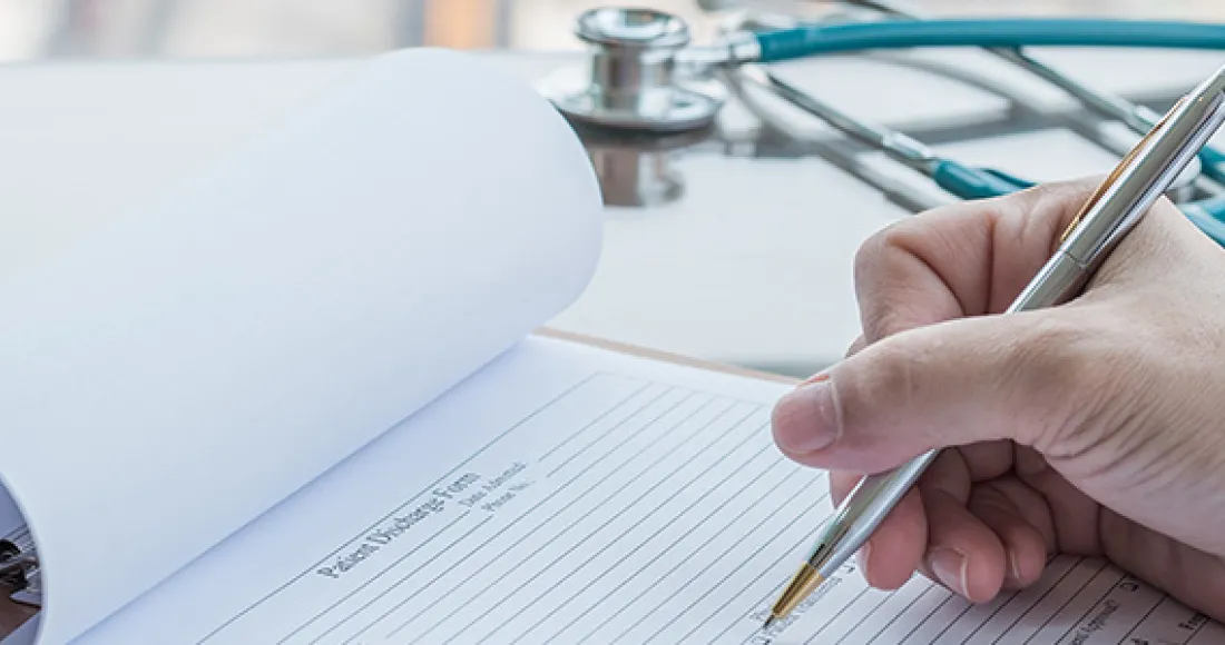 Healthcare worker writing on chart.