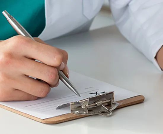 Doctor writing on prescription pad, holding pill bottle.